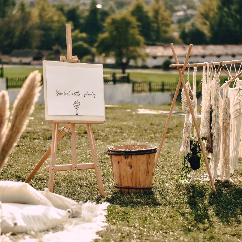 Ambiance bohème pour un enterrement de vie de jeune fille organisé en extérieur, avec chevalet, macramé et décoration naturelle par l’Agence Moment de Grâce.